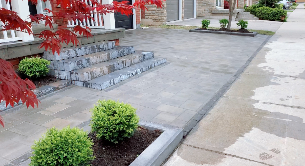Paver driveway, stone entrance steps and a raised planting bed