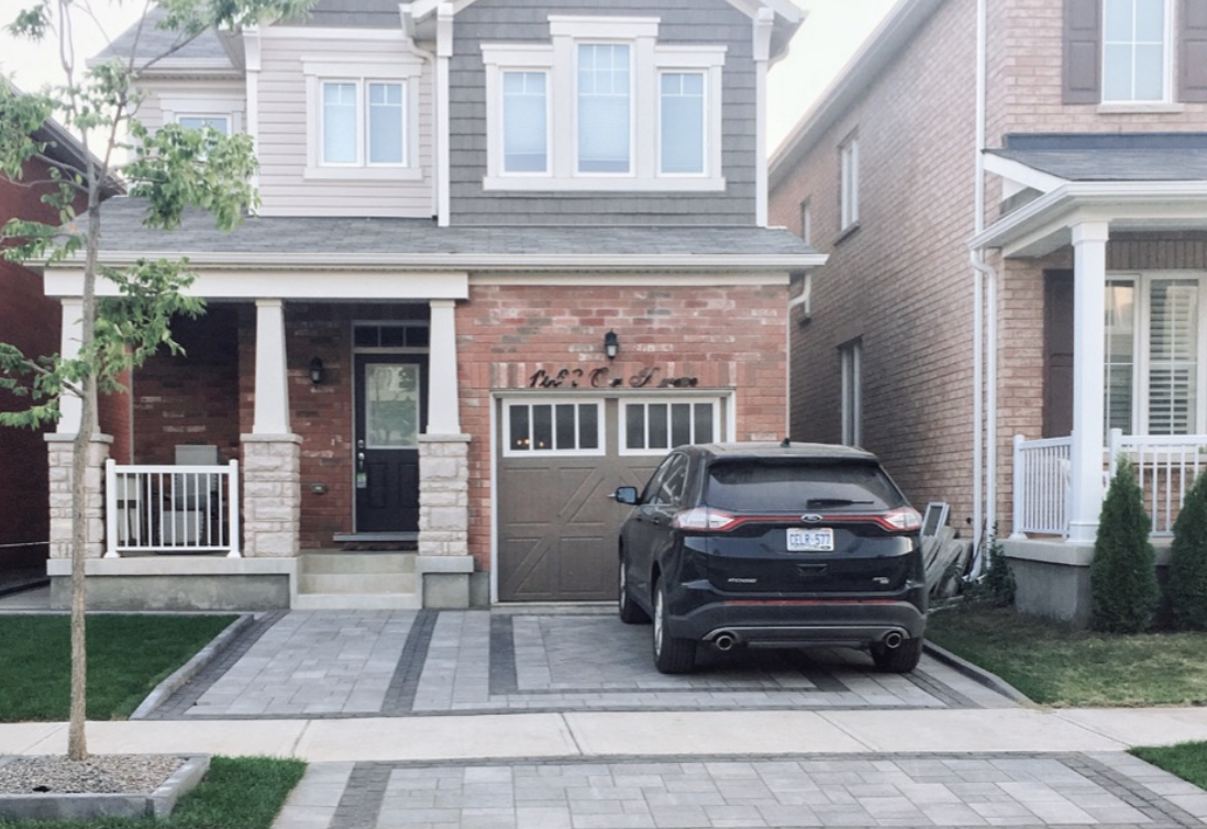 Interlocking driveway with contrasting linear borders in front of a brick home