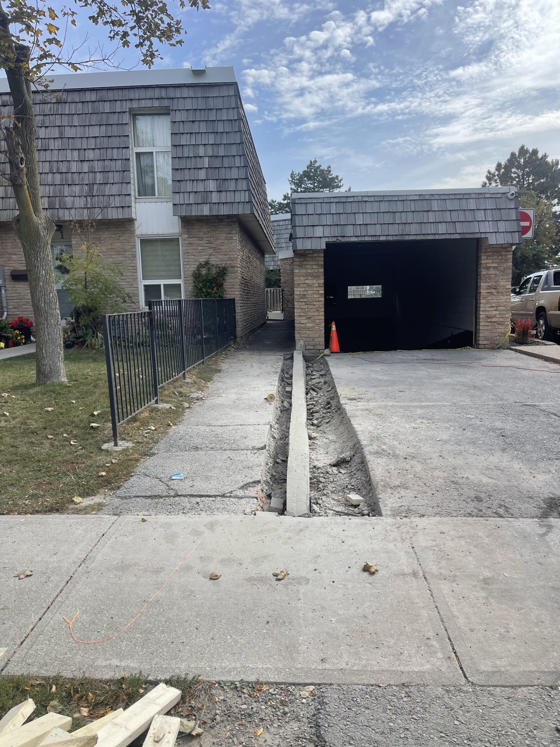 Residential driveway under construction showing fresh concrete curb installation and excavation work in progress.