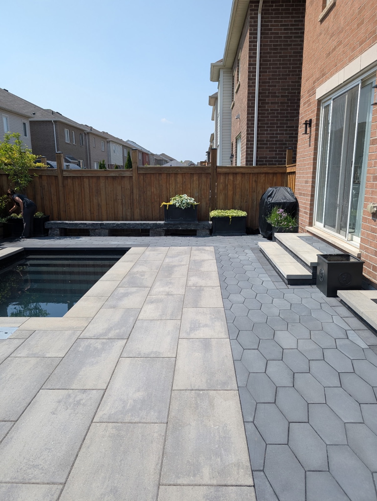 Modern backyard with rectangular pool, large format porcelain pavers, hexagonal interlocking pathway, and raised planters