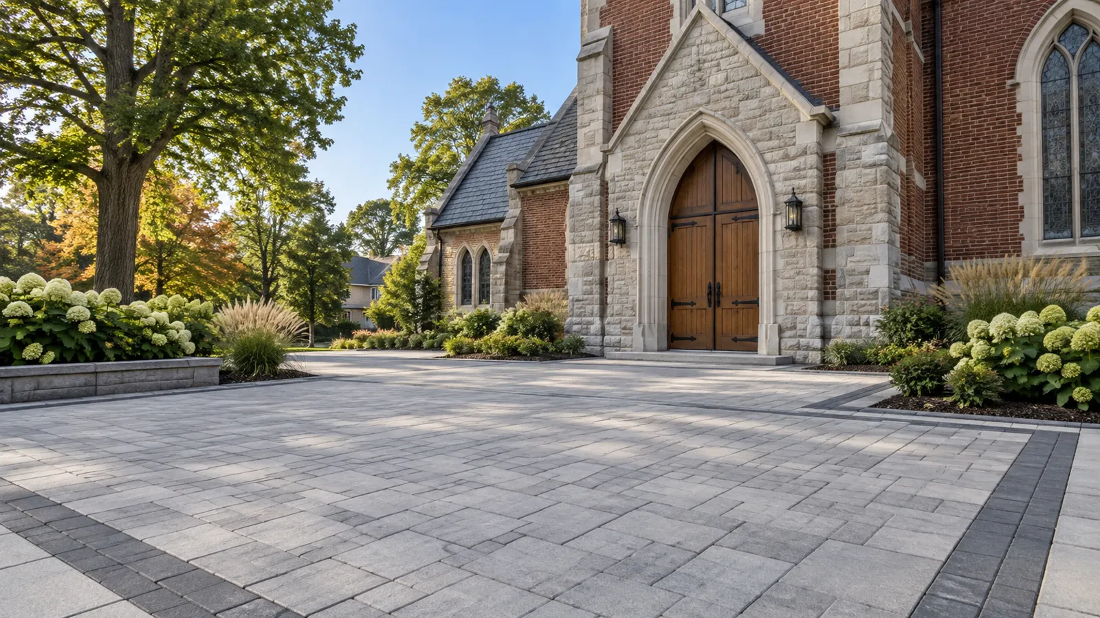 a stone church entrance with grey paver forecourt and hydrangea planting
